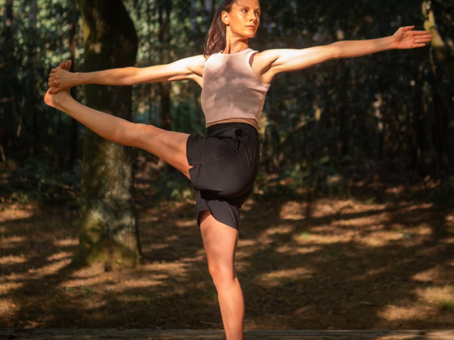 Elisa McCoy en equilibrio sobre una pierna, en el bosque